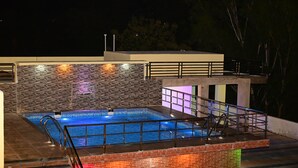 A swimming pool with a tiled deck and a metal railing. - Hotel Prince Nayagarh (Nayagarh)