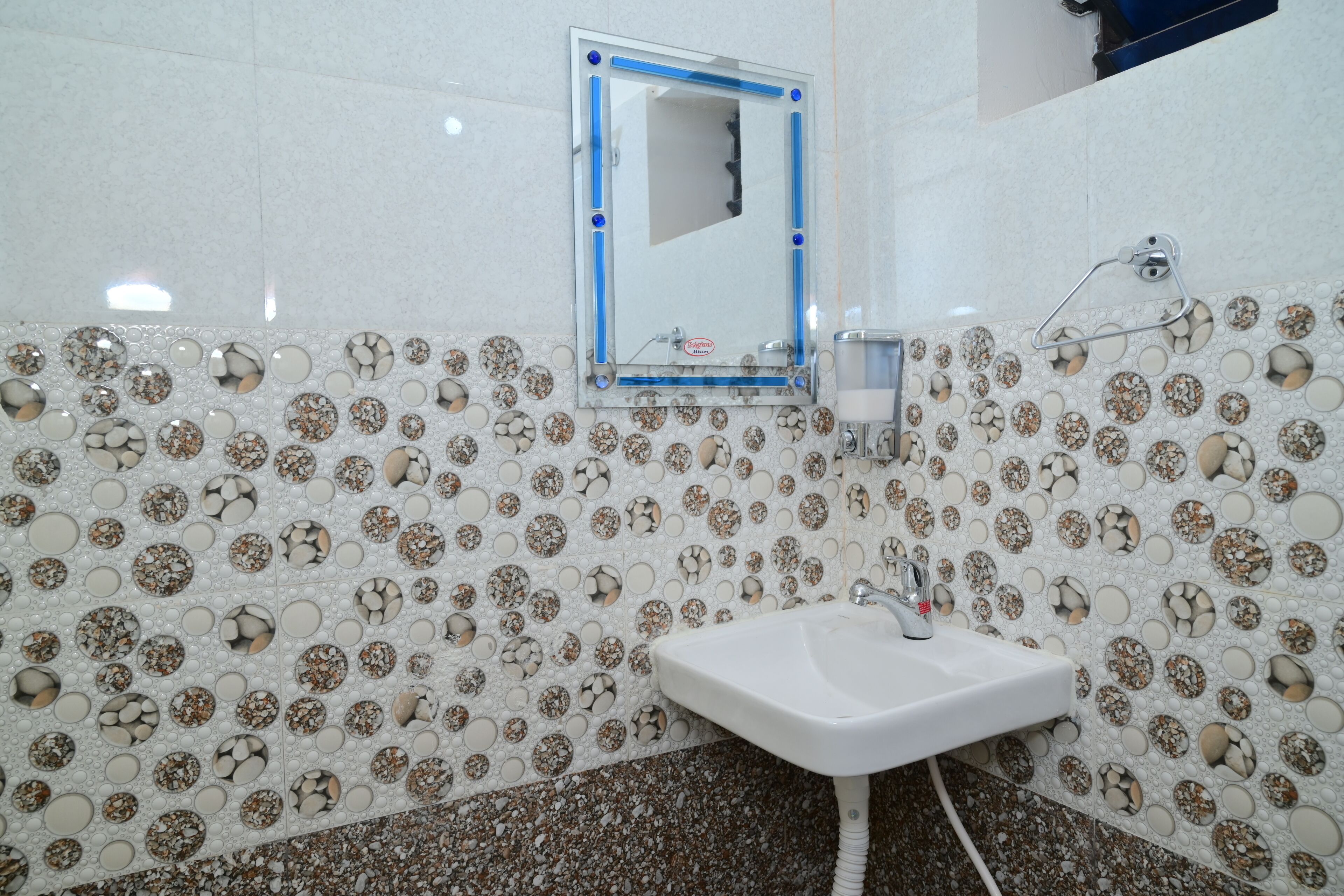 Een badkamer met een wastafel, spiegel en decoratieve betegelde muur.