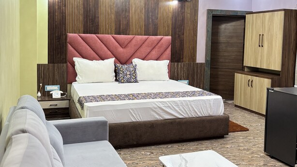 A modern bedroom with a large bed, a sofa, a small table, and a wardrobe. - Hotel Prince Nayagarh (Nayagarh)