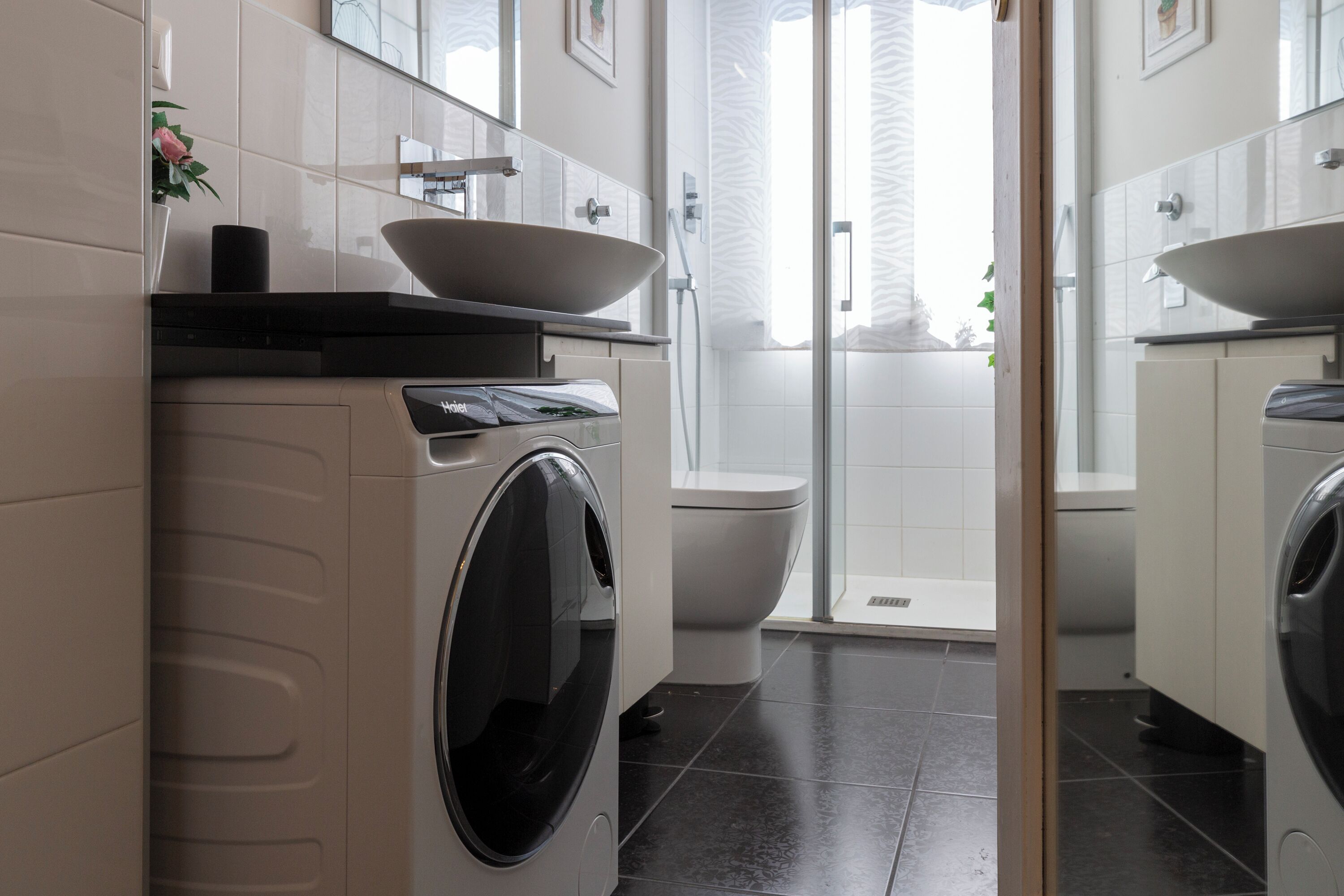 A modern bathroom with a washing machine, a sink, and a toilet.