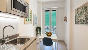 Une cuisine moderne équipée d’un four à micro-ondes encastré, d’un évier en acier inoxydable et d’un saladier rempli de fruits posé sur la table.
