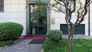 Une entrée d’immeuble avec une porte verte, des marches en pierre et un tapis rouge.