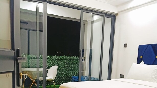A bedroom with a bed, a sliding glass door to a balcony, and a small table with chairs. - Gatundu Heights Apartments Kileleshwa (Nairobi)