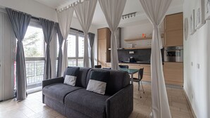 A modern living room with a grey sofa, a dining table, and a kitchen in the background. - Italianway Comfort - Savona 123 (Milan)