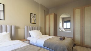 A hotel room with two beds, a large wardrobe, and a window with a view.