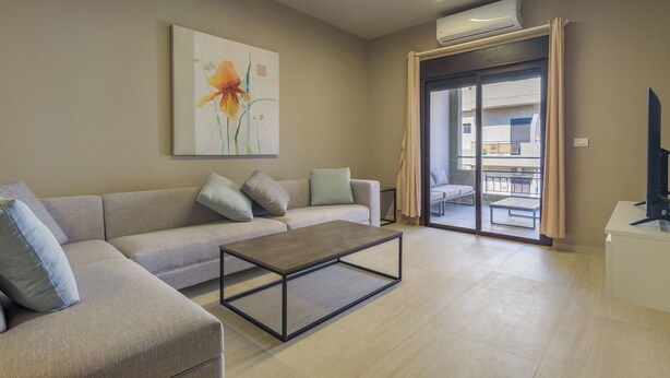 A modern living room with a sofa, a coffee table, and a painting on the wall.