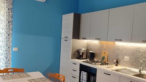 A compact kitchen with white cabinets, a countertop with a coffee machine, and a sink. - Turiddu Apartment- Casa Vacanze Giardini Naxos (Taormina)