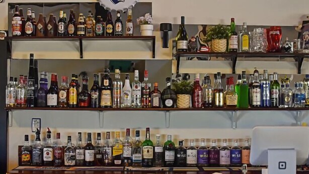 Un bar amb diverses prestatgeries plenes de diferents ampolles d'alcohol.