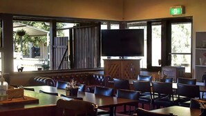 Un restaurant amb un gran televisor, seients a cabines i una barra.