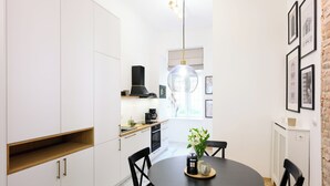 Una cocina moderna con armarios blancos, una mesa redonda para comer y sillas negras.