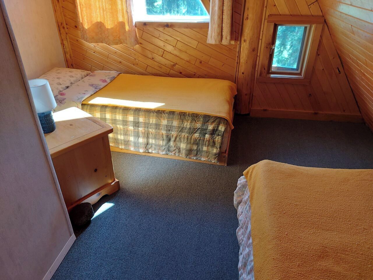 Een knus kamertje met een bed, nachtkastje en een raam.