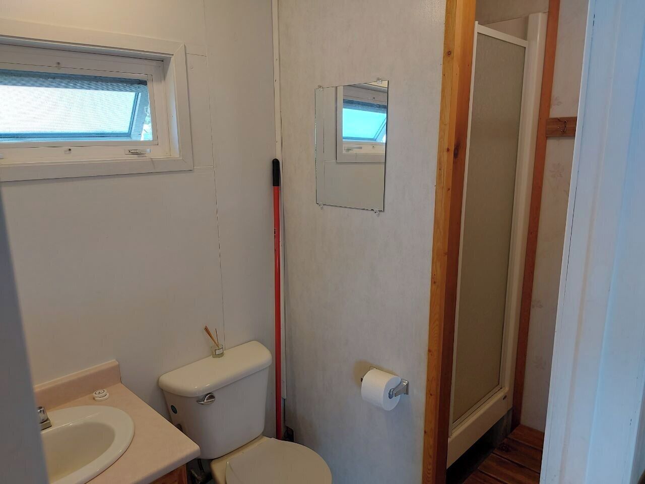 Une petite salle de bain compacte, équipée de toilettes, d’un lavabo et d’une fenêtre.