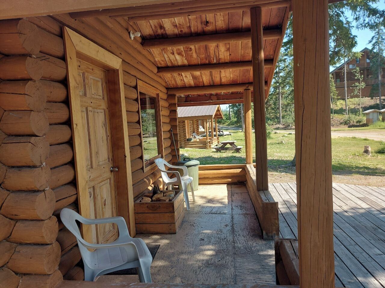 Una cabaña de troncos con un porche, bancos de madera y una mesa de picnic.