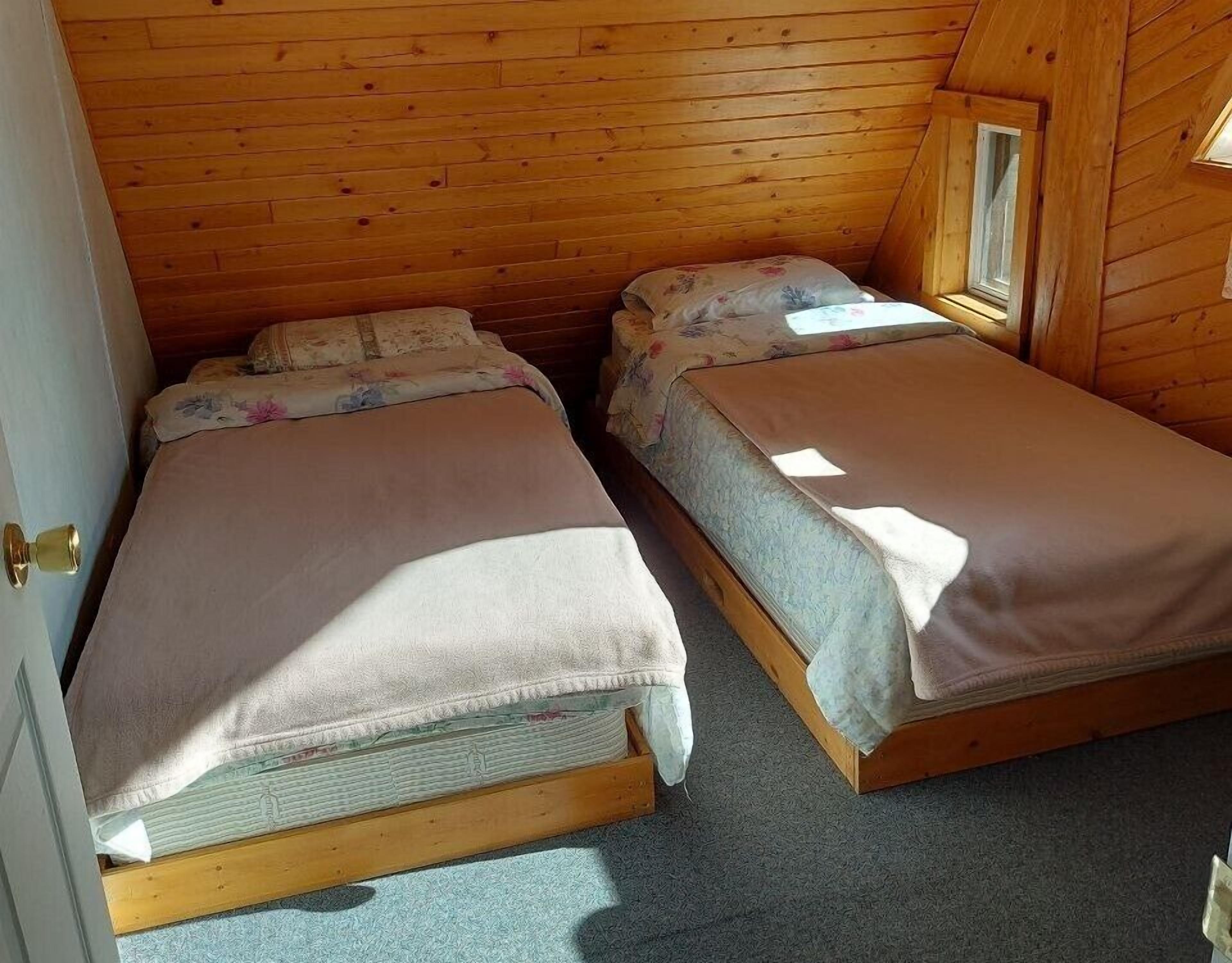 A small, cozy room with two wooden bunk beds, a window, and a door.