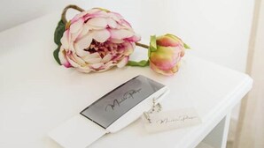 A white table with a name tag, a decorative flower, and a small white box.