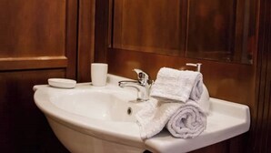 A bathroom sink with a white basin, a silver faucet, and a rolled white towel on the side.