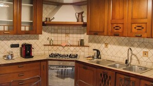 A kitchen with wooden cabinets, a gas stove, a coffee maker, and a sink.