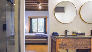 A bathroom with a shower, a sink with a mirror, and a window with curtains. - Pet Friendly Loft / Rooftop Hot Tub & Views (Fernie)