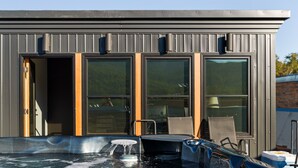 A modern building with large windows, a hot tub, and outdoor seating. - Pet Friendly Loft / Rooftop Hot Tub & Views (Fernie)