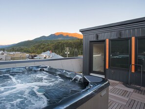 A hot tub on a rooftop with a view of mountains and a modern building with large windows. - Pet Friendly Loft / Rooftop Hot Tub & Views (Fernie)