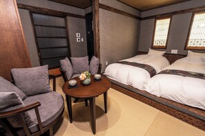 Ein Hotelzimmer mit Sofa, einem kleinen Tisch mit Vase und zwei Schalen, sowie einem Bett mit weißer Bettwäsche.