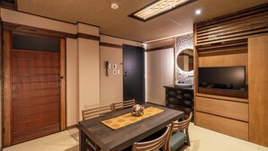Un coin repas avec une table en bois, des chaises et un téléviseur posé sur un meuble en bois.
