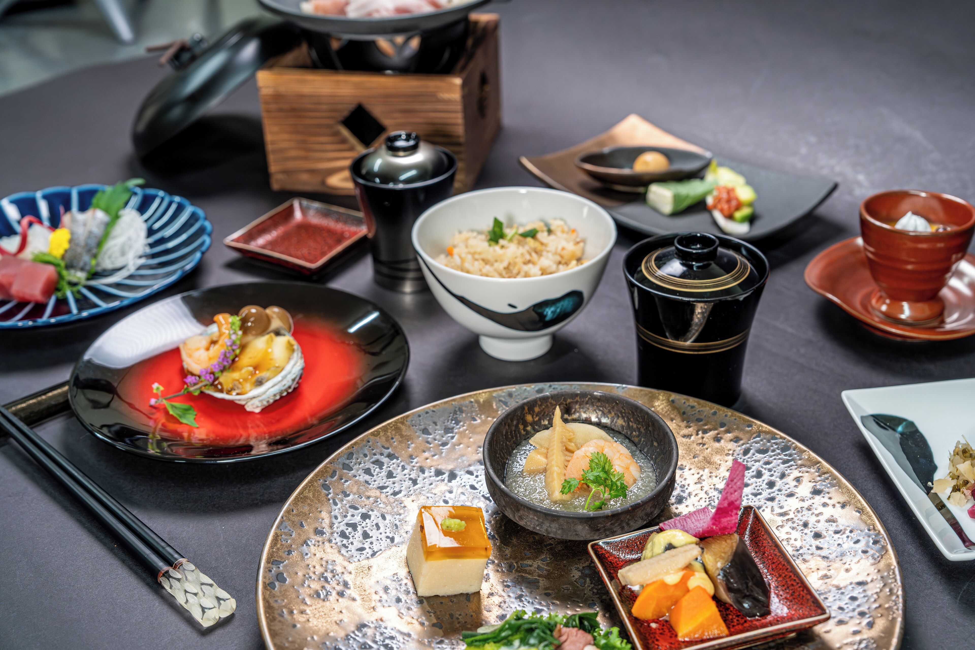 A variety of dishes on a table, including sushi, rice, and a bowl of soup.