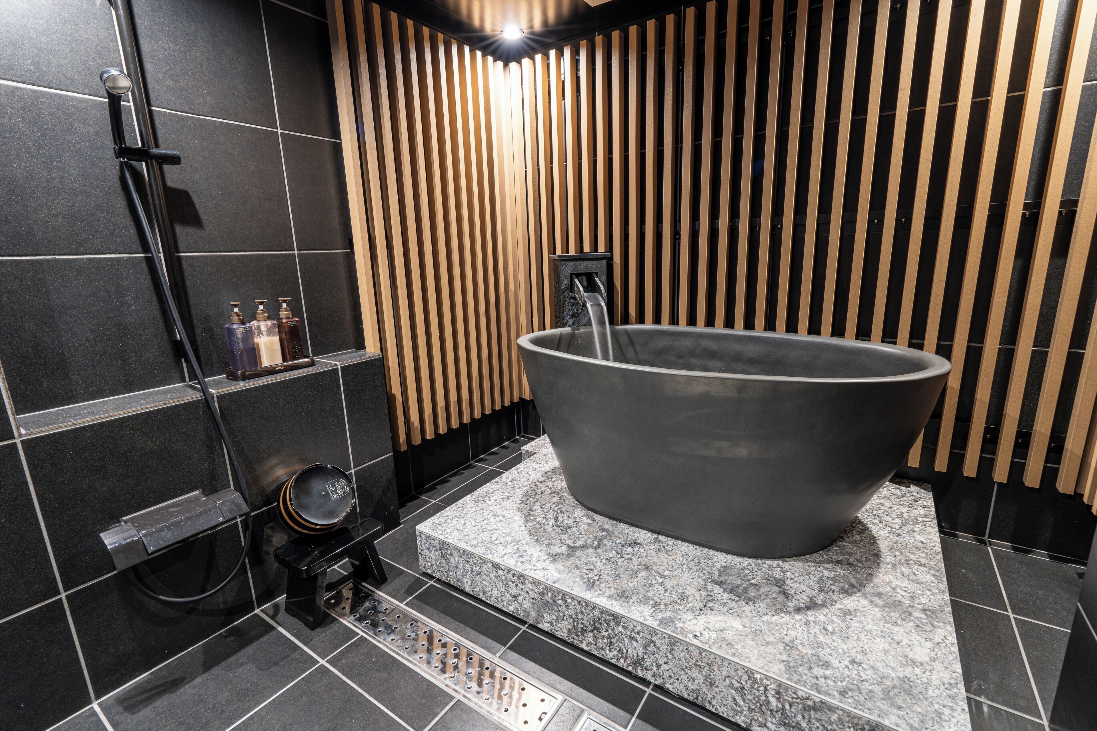 Un baño moderno con una bañera independiente, zona de ducha y suelo de baldosas.
