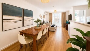 Un comedor con una mesa y sillas de madera, un cuadro grande en la pared y una lámpara colgante.