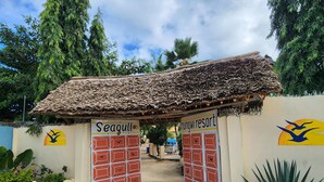 A resort entrance with a thatched roof, two gates labeled "Seagull" and "Nungwi Resort", surrounded by greenery. - Seagull Nungwi Resort (Nungwi)