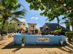 Un complexe hôtelier doté d’une piscine, de palmiers et d’un panneau indiquant « Seagull ».