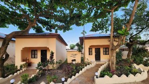 A row of two-story buildings with a central pathway, surrounded by landscaped gardens and trees. - Seagull Nungwi Resort (Nungwi)