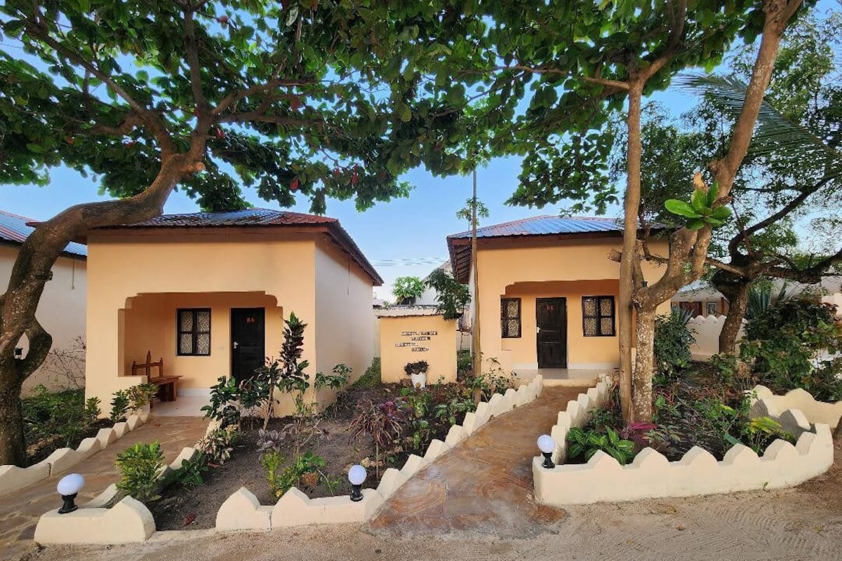 A row of two-story buildings with a central pathway, surrounded by landscaped gardens and trees.