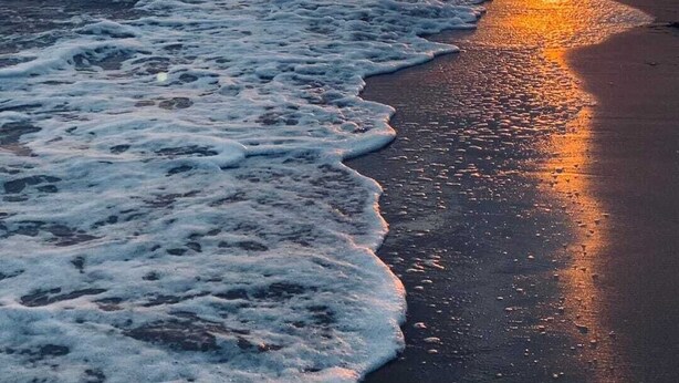 Une plage avec des vagues au coucher du soleil.