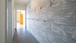 A hallway with a patterned wallpaper featuring sailboats and a wooden door.