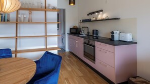 A modern kitchen with wooden shelves, a dining table, and chairs.