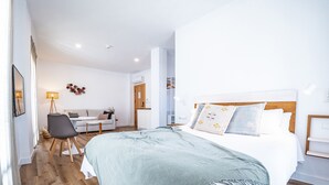 A modern hotel room with a large bed, a desk, and a chair. - Posada El Convento Superior Deluxe Studio (Ayamonte)