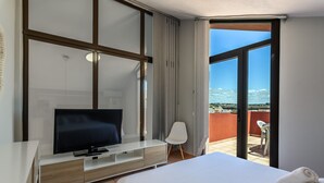 Une chambre d’hôtel moderne dotée d’un grand lit, d’un téléviseur à écran plat, d’une chaise blanche et d’un balcon avec vue.