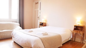 Une chambre d’hôtel avec un grand lit, un canapé, deux tables de chevet avec des lampes et une fenêtre avec des rideaux.