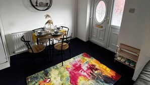 A dining area with a round table, chairs, and a colorful rug. - Cozy 2 Bedhouse 20mins From Manchester City Centre (Oldham)
