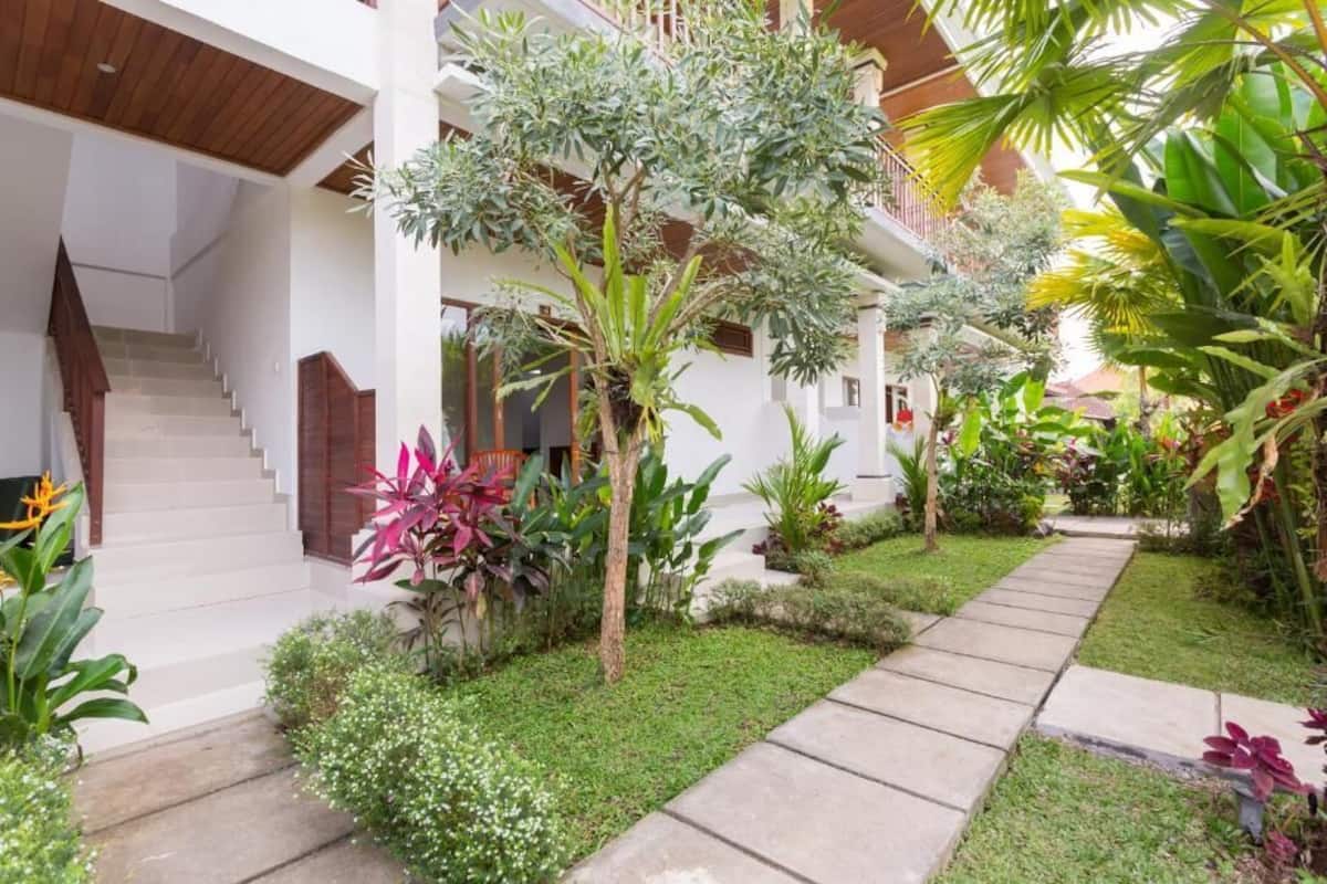 A multi-level building with a staircase, lush greenery, and a pathway.