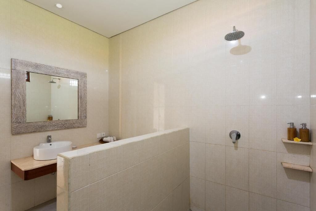 A modern bathroom with a large mirror, a sink, a shower, and a toilet.