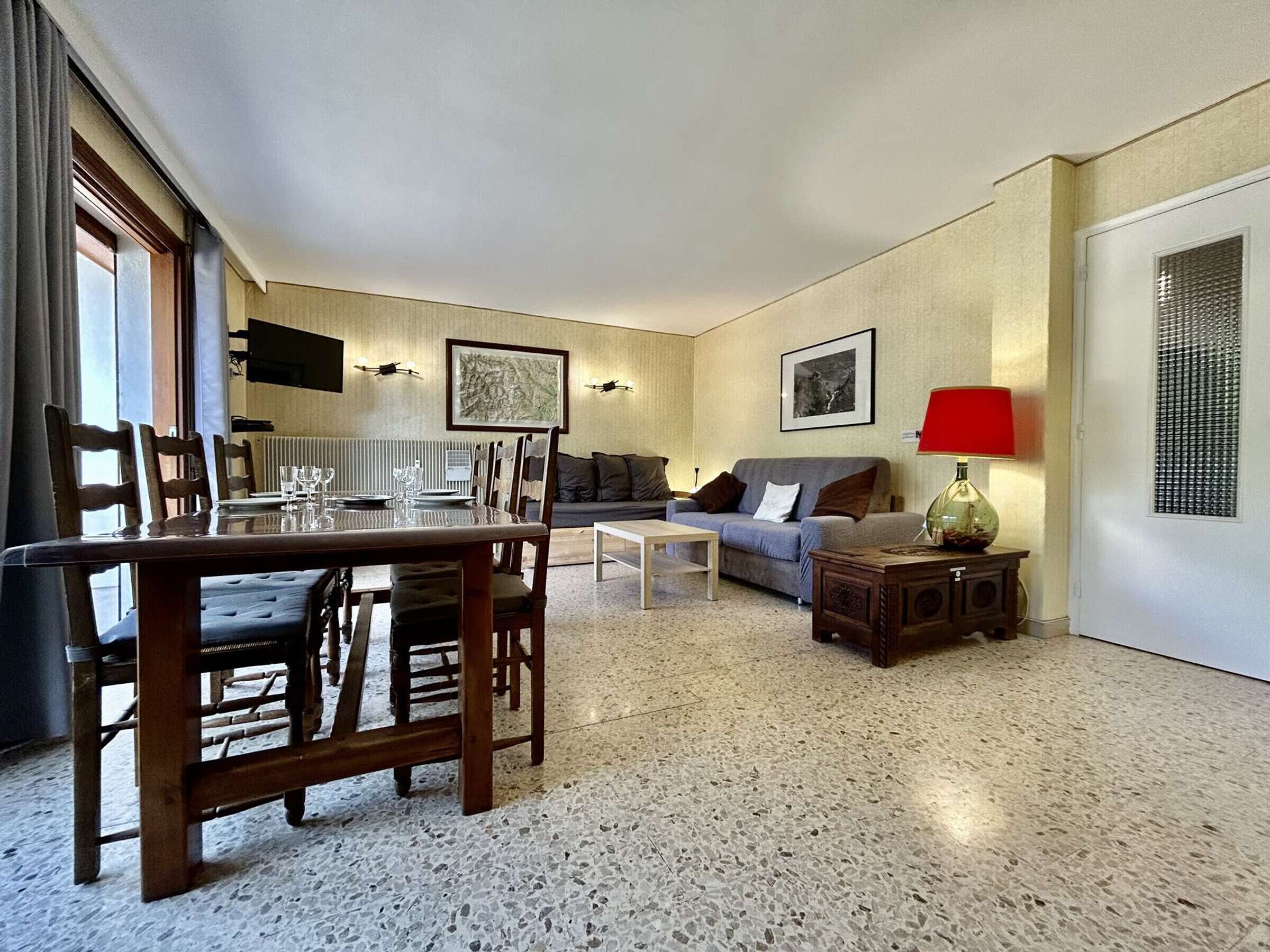 Una sala de estar con una mesa de comedor, sofá y una lámpara roja.