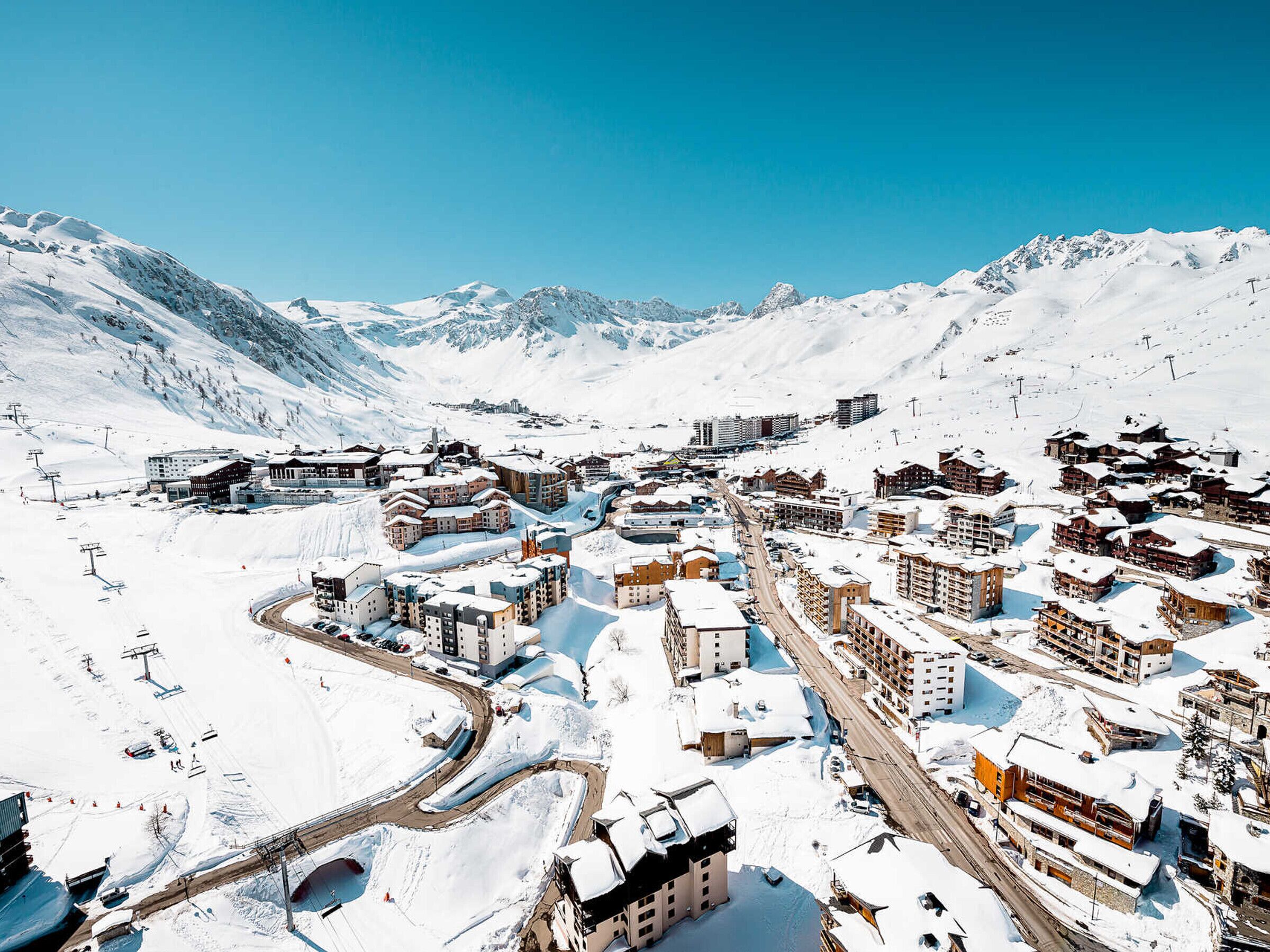 Un paese montano innevato con edifici, strade e piste da sci.