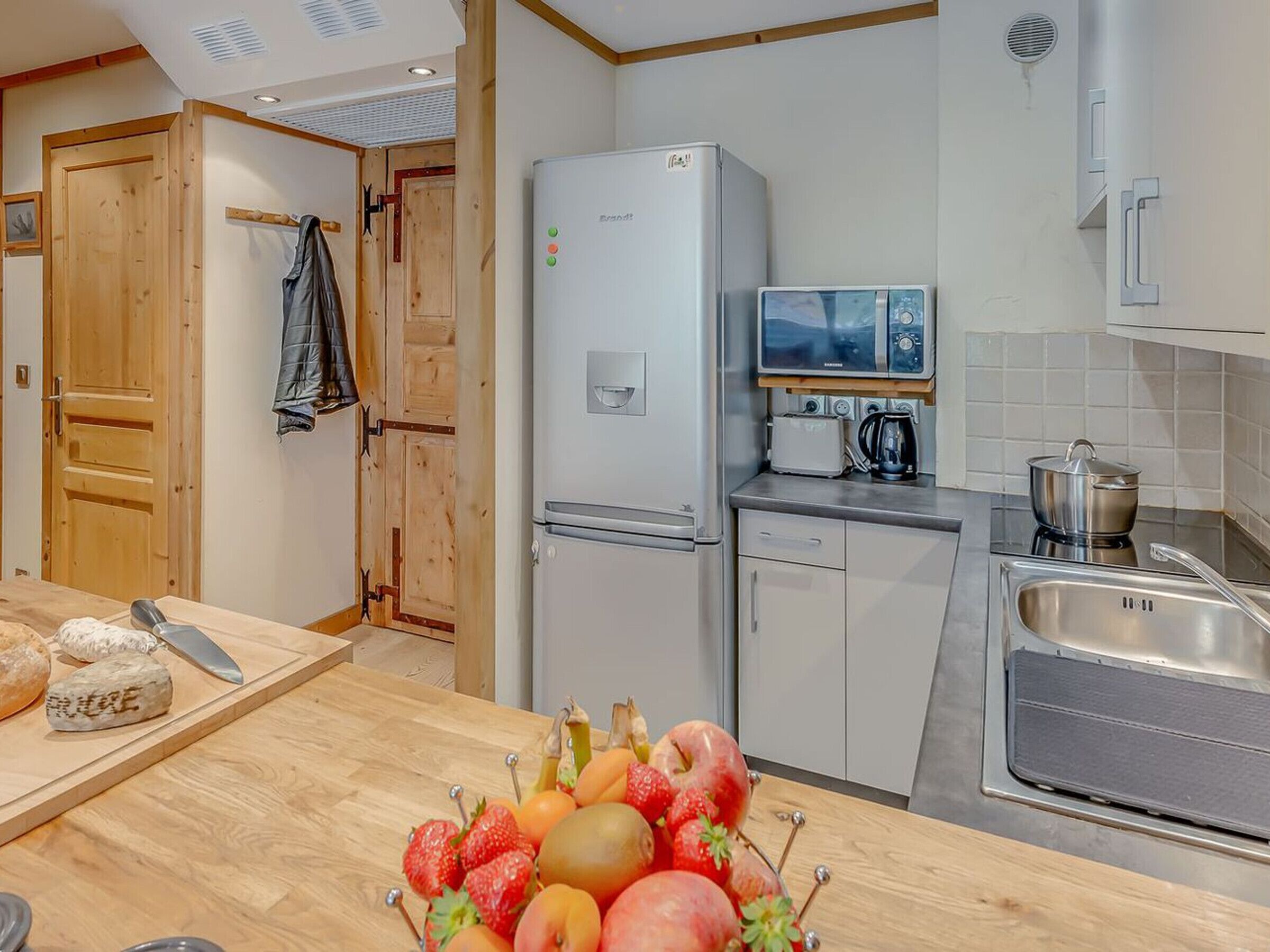 A compact kitchen with a refrigerator, microwave, and sink.