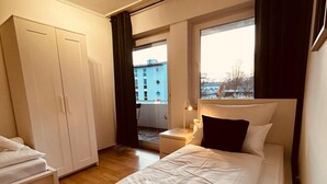 A hotel room with a bed, a bedside table, a lamp, a window, and a wardrobe. - B23 Monteureiteamsi3zimmeritv (Ibbenbüren)