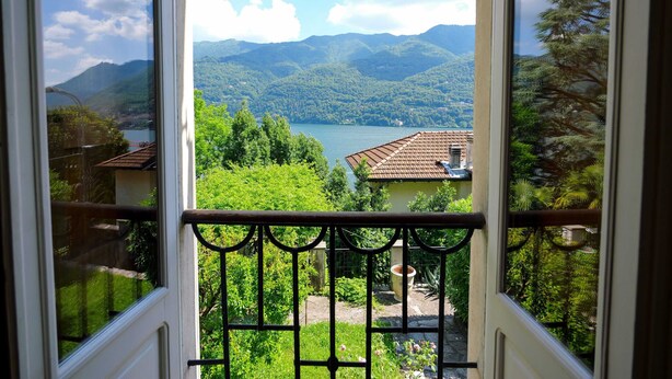 A balcony with a metal railing overlooking a mountainous landscape and a lake. - Pottery Mansion (Argegno)