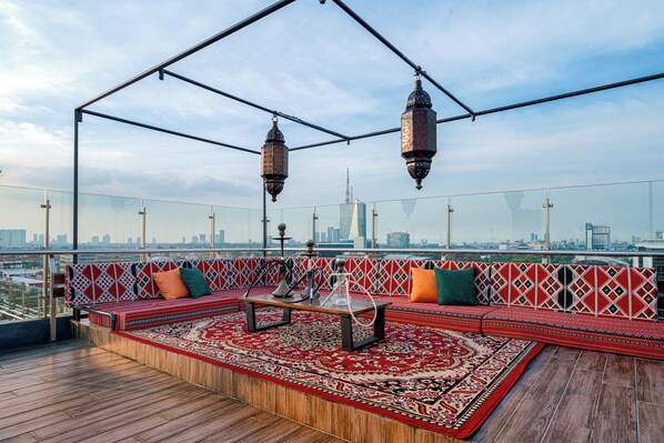A rooftop lounge with a patterned sofa, a coffee table, and hanging lanterns. - Excotel Design Hotel  (Surabaya)