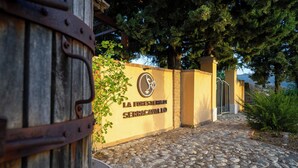 Un sendero de piedra que conduce a una entrada con puerta de hierro, con un letrero que dice "LA FORESTIERIA SERRACAVALLO".