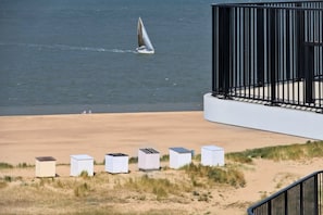 A beach with a sailboat, a fence, and several white structures.